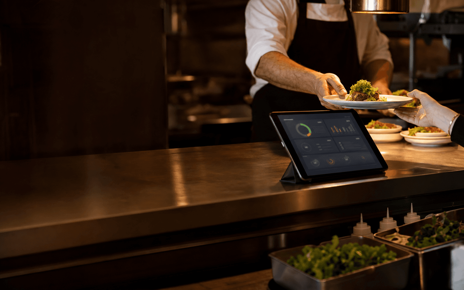 Restaurant kitchen pass with an operations dashboard on a tablet